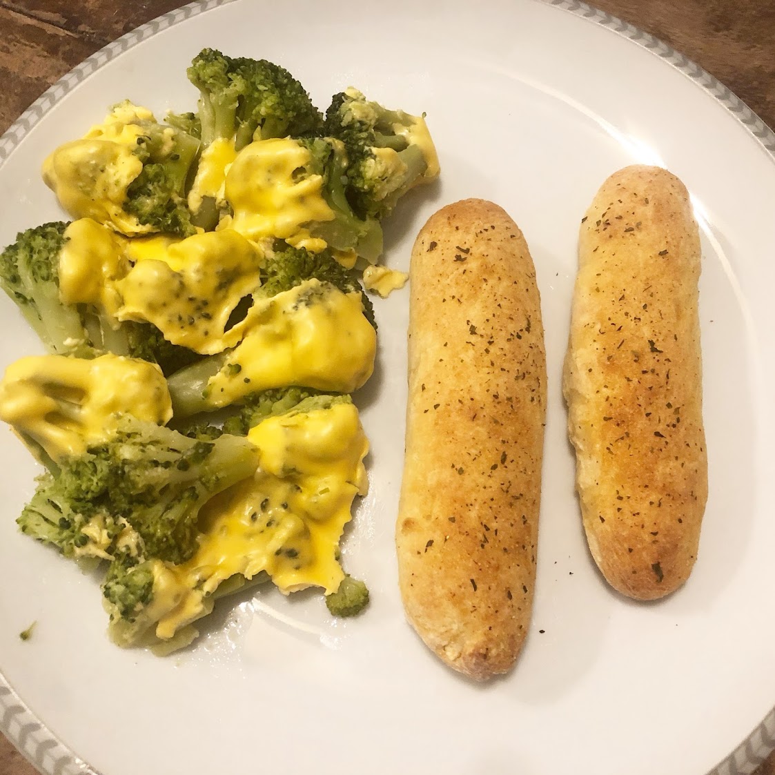 Two 2-ingredient dough breadsticks and broccoli with melted cheese on top